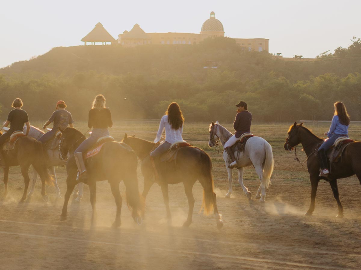 Cabalgata entre palmeras con la arquitectura de Cuixmala al fondo
