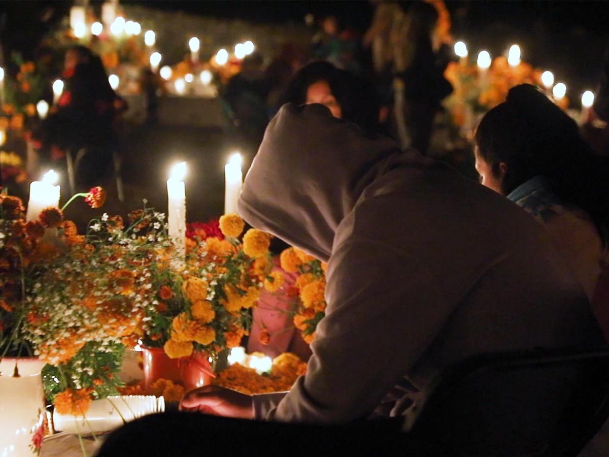 Familia durante la velación de Día de Muertos entre flores y velas